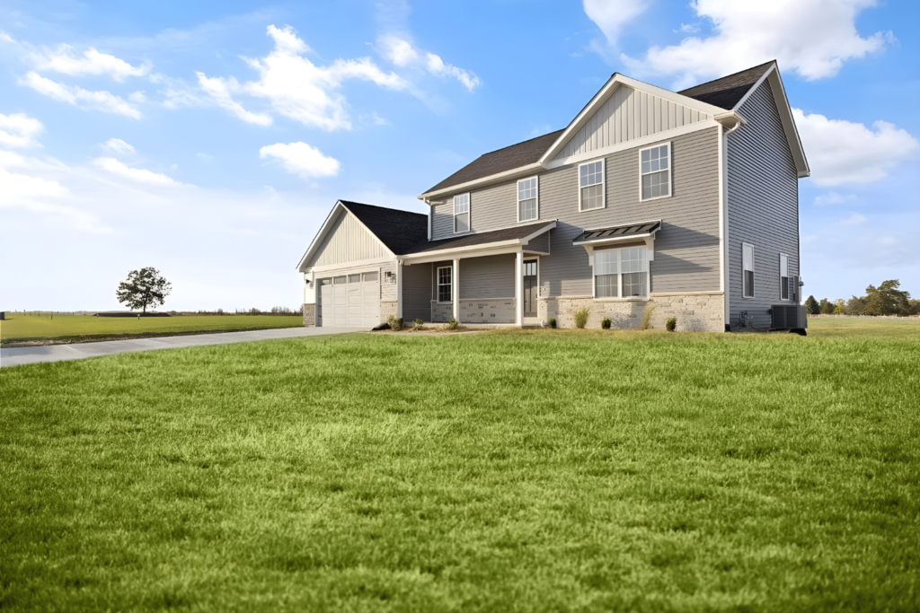 Suburban two-story house with a garage on a large grassy lot under a blue sky