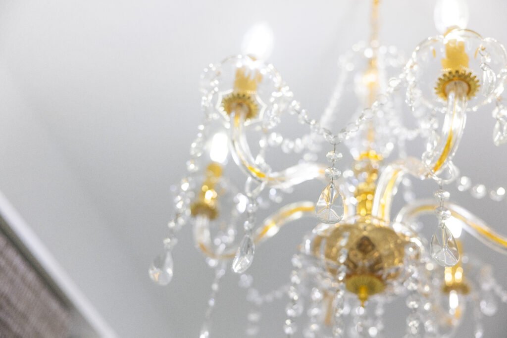 Crystal chandelier with gold accents and hanging teardrop prisms against a white ceiling