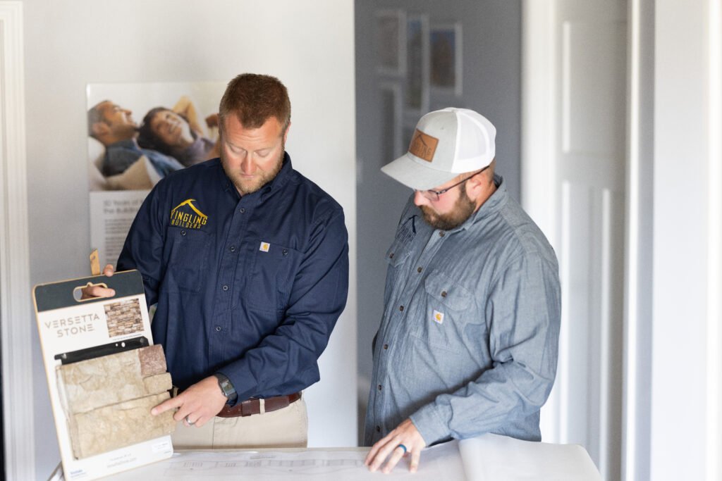 Two builders review plans and stone samples for a home project