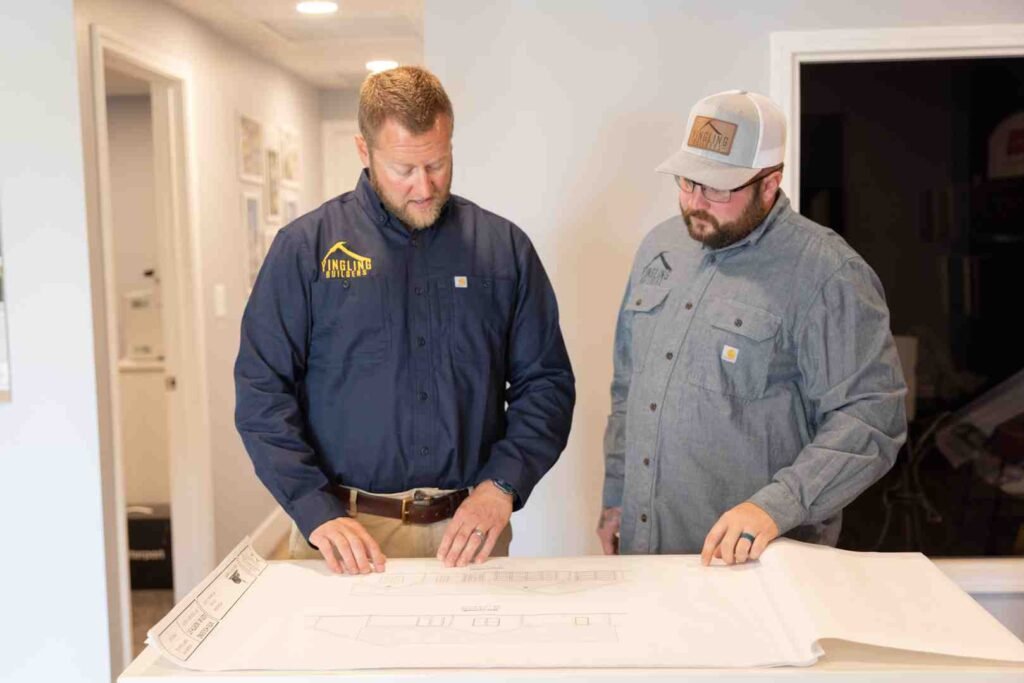 Two construction workers reviewing blueprints indoors