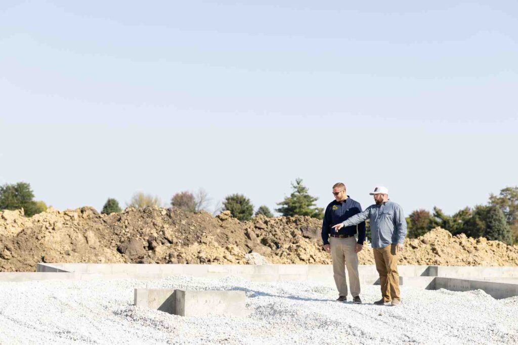 Two men inspect a concrete foundation at a construction site