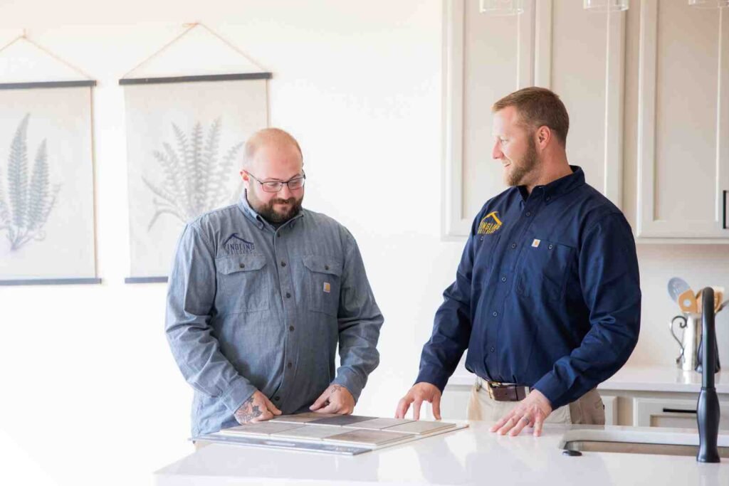 Two men in work shirts reviewing countertop samples in a kitchen showroom
