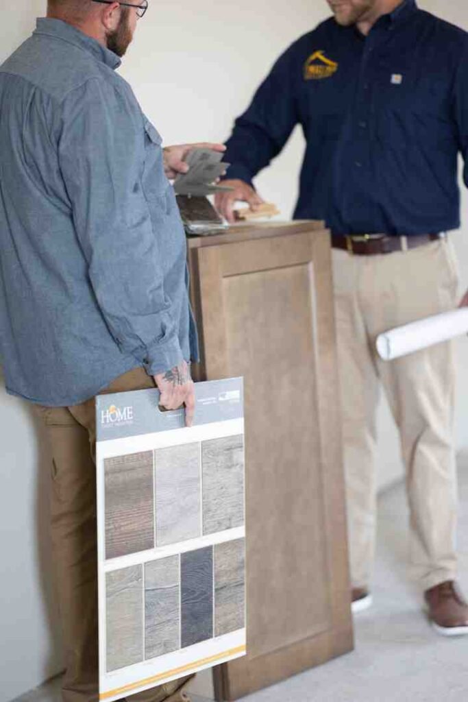 Man holding a flooring sample board while talking with a contractor at a counter