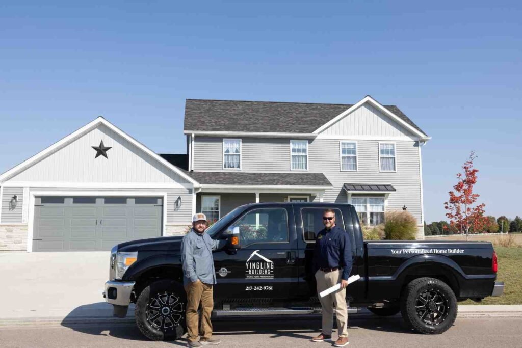 Two men standing beside a black Yingling Builders pickup truck in front of a suburban house