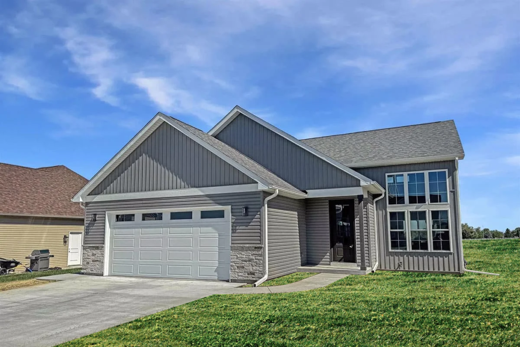 Suburban house with a two-car garage and large front windows under a blue sky