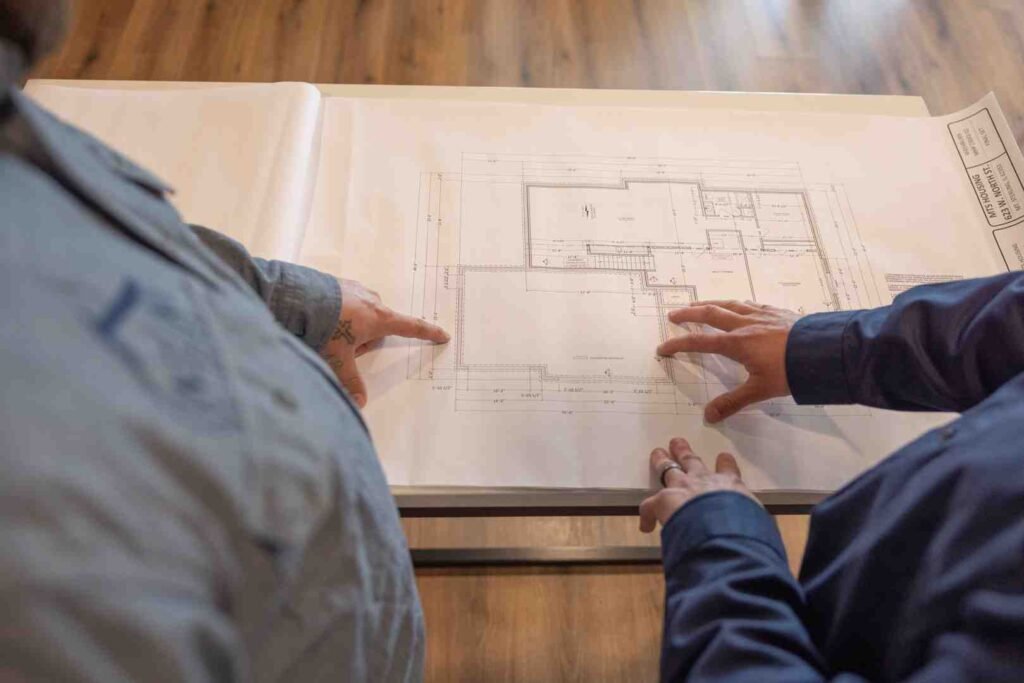 Two people reviewing a house floor plan blueprint on a table