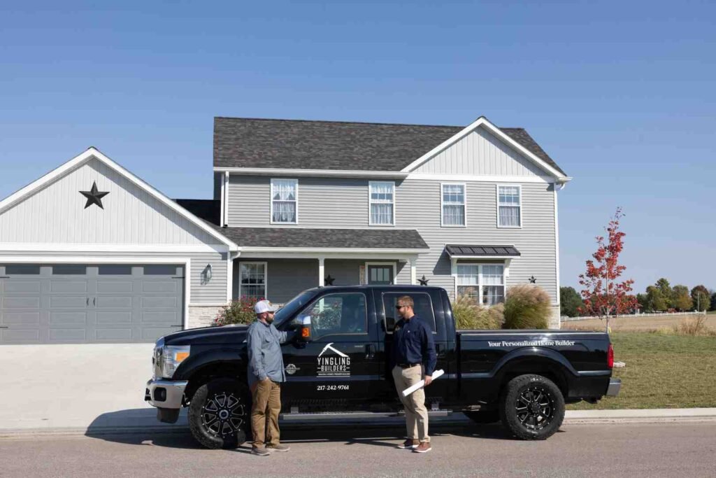 Two men talking beside a Yingling Builders pickup truck in front of a suburban house under construction
