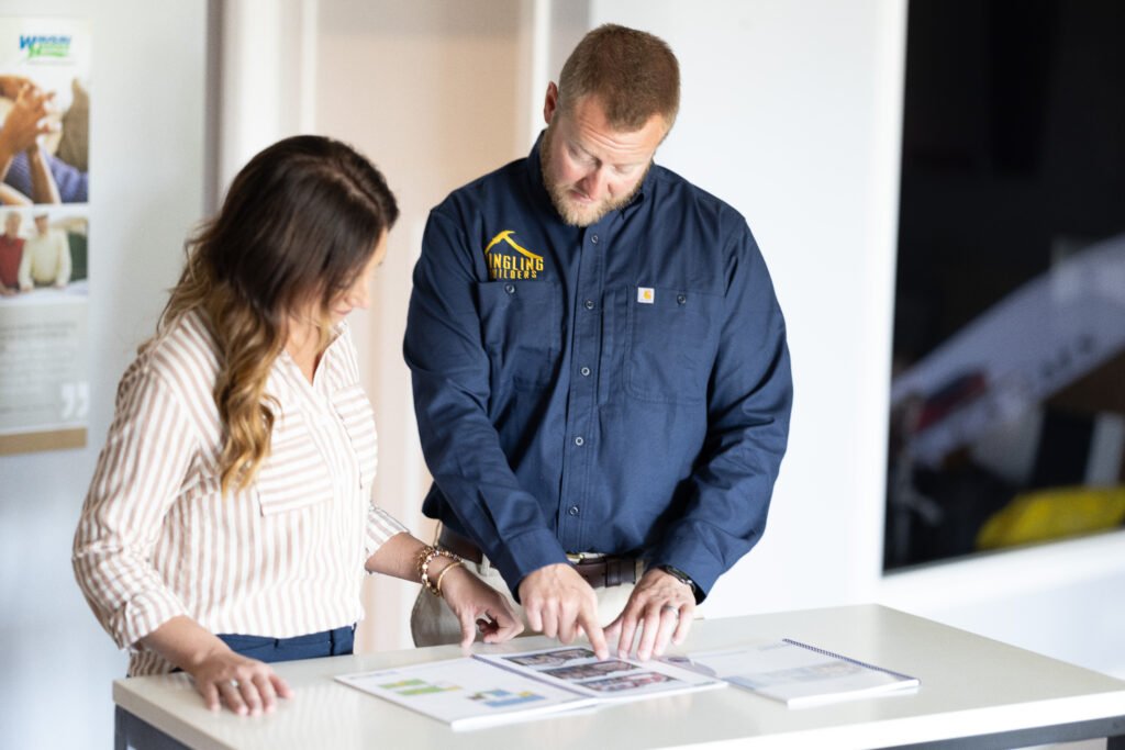Two people review printed materials on a table in an office