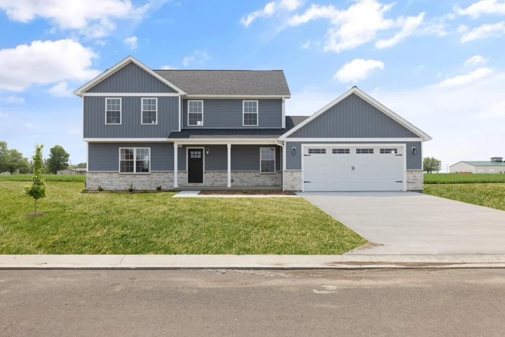 Two-story gray house with a two-car garage and a front lawn under a blue sky
