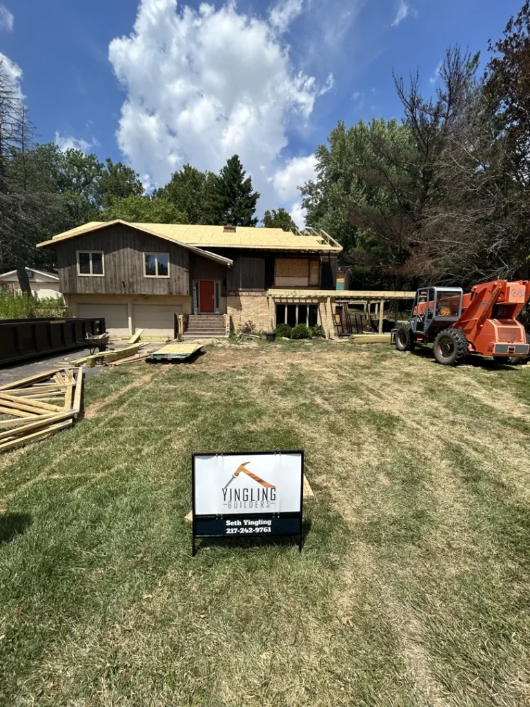 House under renovation with construction materials, a lift, and a Yingling Builders sign in the yard