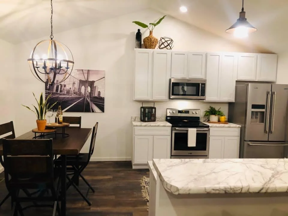 Modern kitchen and dining area with white cabinets, stainless steel appliances, and a dark wood table